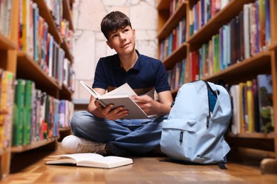 Photo of Student with book on floor in library