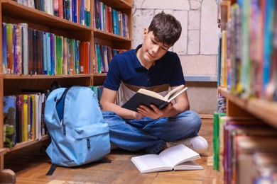 Photo of Student reading book on floor in library
