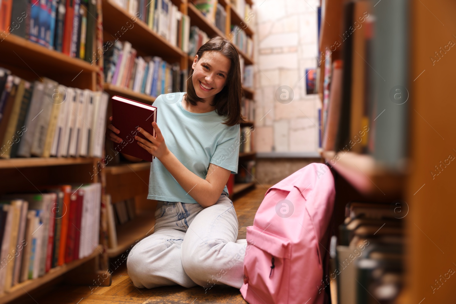 Photo of Student with book on floor in library