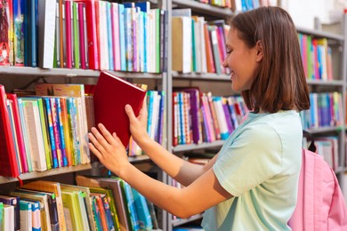 Photo of Student taking book out of shelf in library