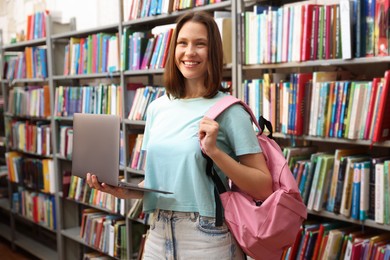 Photo of Student with laptop and backpack in library