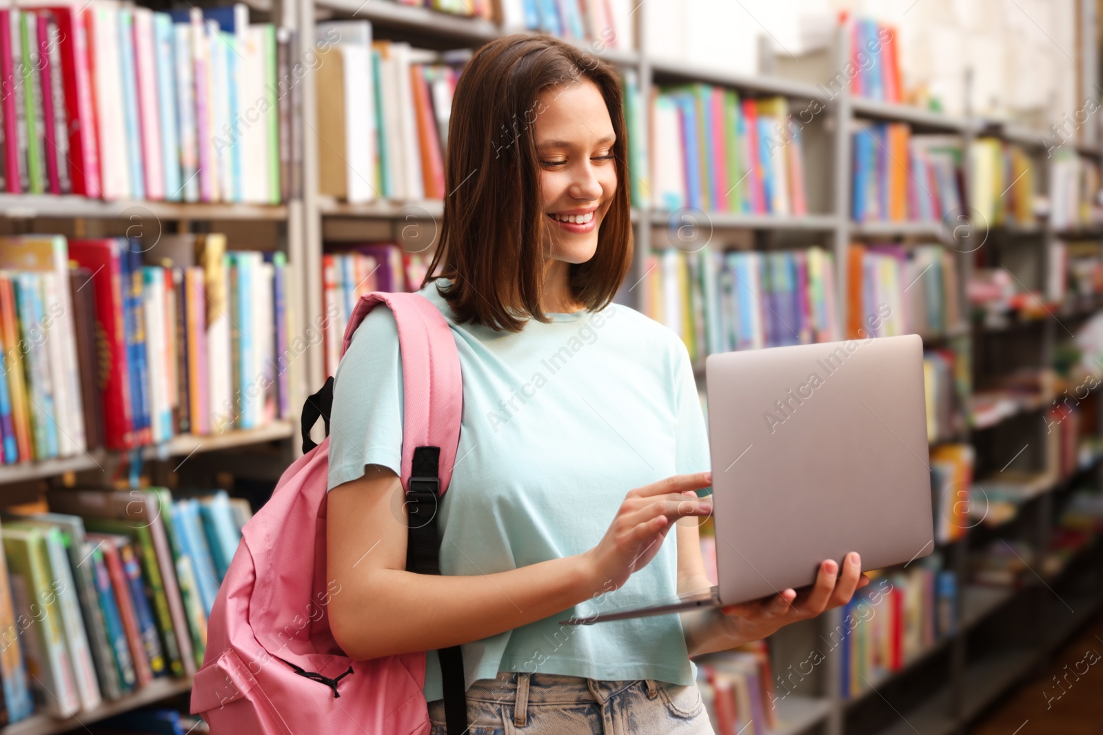Student with laptop and backpack in library Photo of Student with laptop and backpack in library