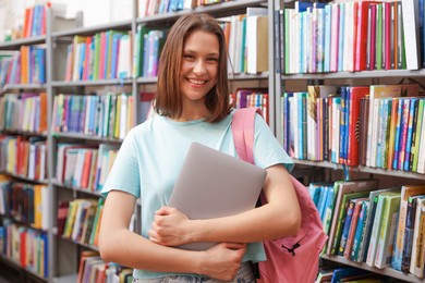 Photo of Student with laptop and backpack in library