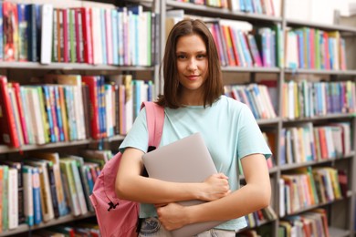 Photo of Student with laptop and backpack in library