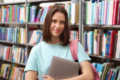 Photo of Student with laptop and backpack in library