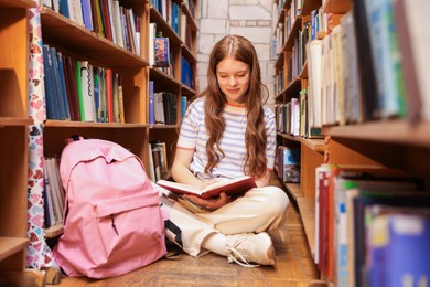 Photo of Student reading book on floor in library
