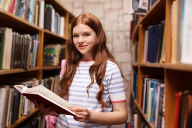 Photo of Student with book and backpack in library