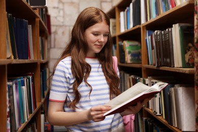 Photo of Student with book and backpack in library