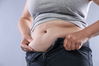 Photo of Woman with excessive belly fat on light background, closeup. Overweight problem