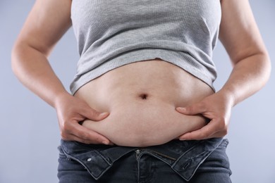 Photo of Woman with excessive belly fat on light background, closeup. Overweight problem