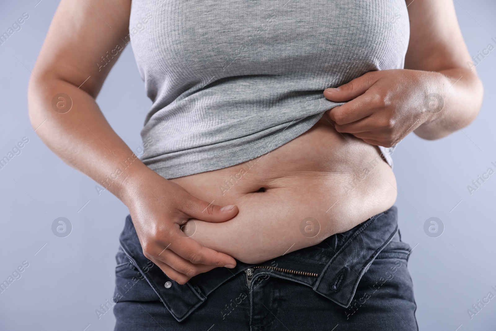 Woman with excessive belly fat on light background, closeup. Overweight problem Photo of Woman with excessive belly fat on light background, closeup. Overweight problem