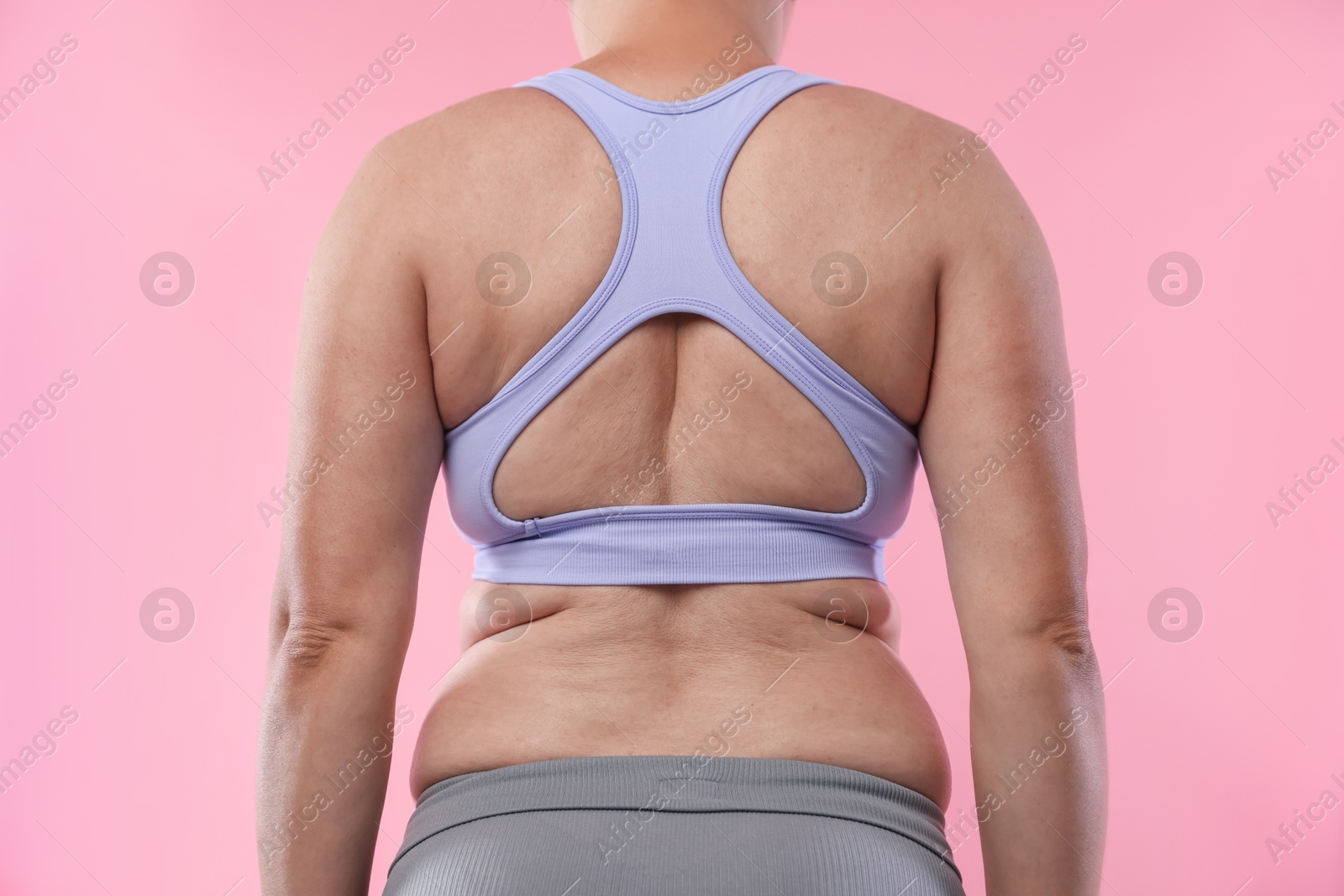 Overweight woman on pink background, back view Photo of Overweight woman on pink background, back view