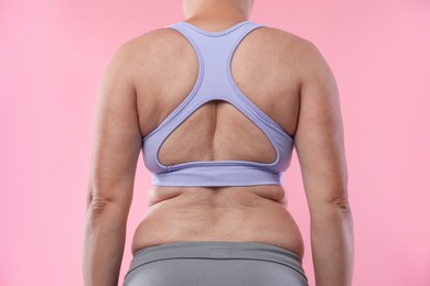 Photo of Overweight woman on pink background, back view