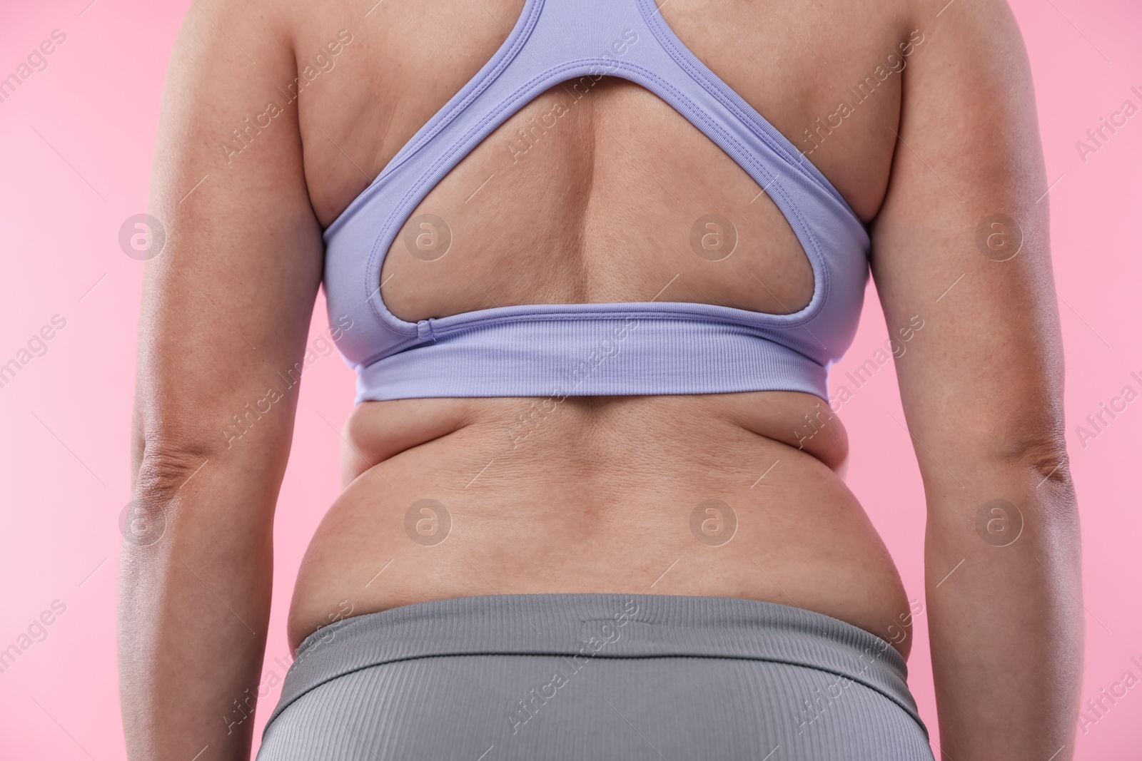 Overweight woman on pink background, back view Photo of Overweight woman on pink background, back view