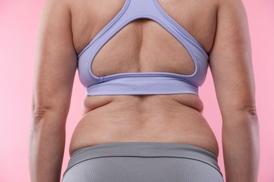 Photo of Overweight woman on pink background, back view
