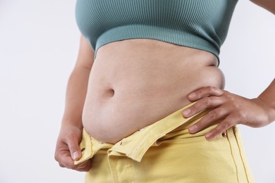 Photo of Woman with excessive belly fat on light background, closeup. Overweight problem