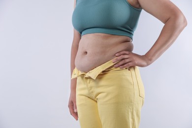 Photo of Woman with excessive belly fat on light background, closeup. Overweight problem