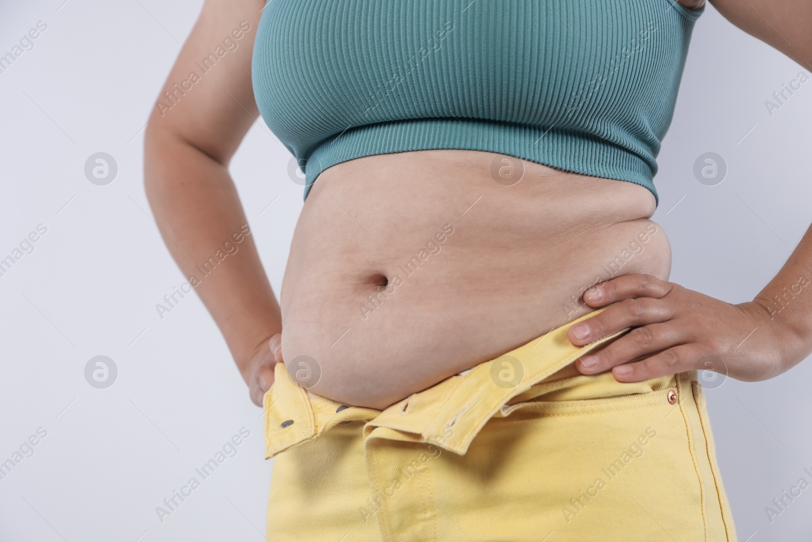Woman with excessive belly fat on light background, closeup. Overweight problem Photo of Woman with excessive belly fat on light background, closeup. Overweight problem