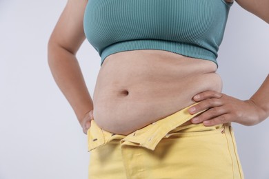 Photo of Woman with excessive belly fat on light background, closeup. Overweight problem
