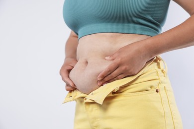Photo of Woman with excessive belly fat on light background, closeup. Overweight problem