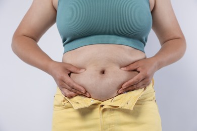 Photo of Woman with excessive belly fat on light background, closeup. Overweight problem