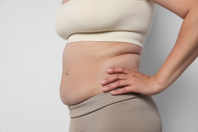 Photo of Woman with excessive belly fat on light background, closeup. Overweight problem