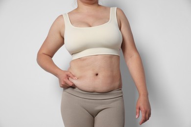 Photo of Woman with excessive belly fat on light background, closeup. Overweight problem