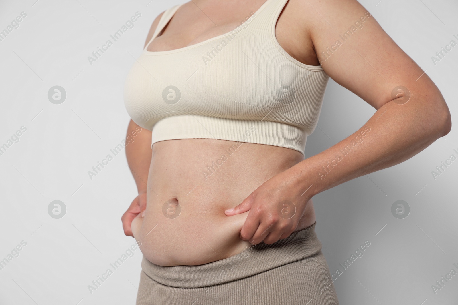 Woman with excessive belly fat on light background, closeup. Overweight problem Photo of Woman with excessive belly fat on light background, closeup. Overweight problem