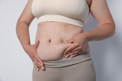Photo of Woman with excessive belly fat on light background, closeup. Overweight problem
