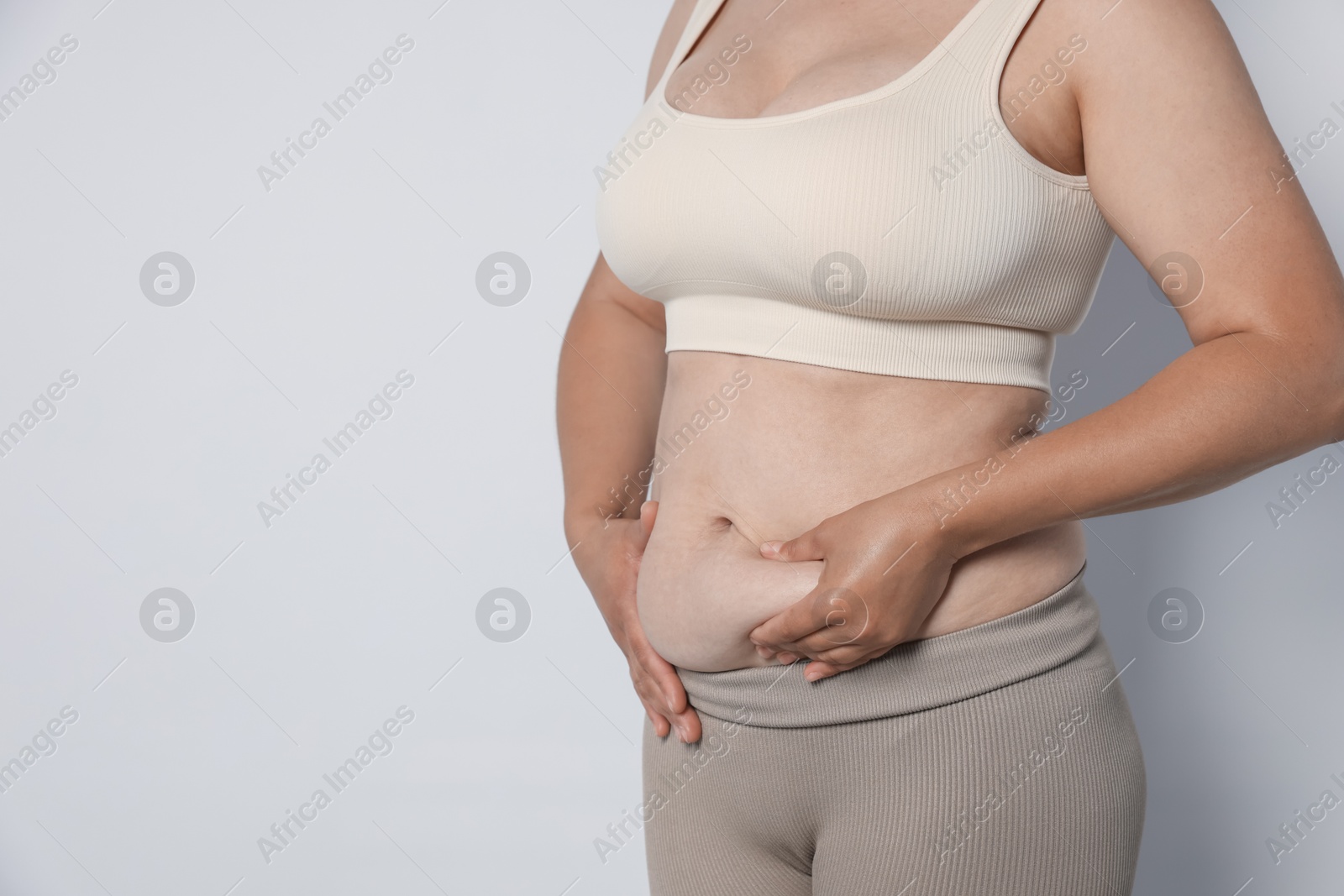 Woman with excessive belly fat on light background, closeup and space for text. Overweight problem Photo of Woman with excessive belly fat on light background, closeup and space for text. Overweight problem