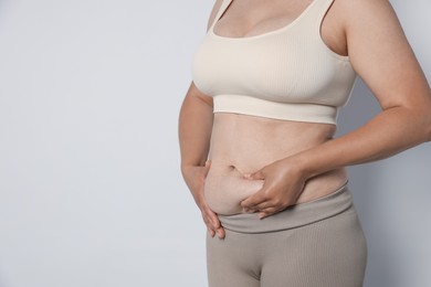 Photo of Woman with excessive belly fat on light background, closeup and space for text. Overweight problem