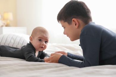 Photo of Cute little brothers holding hands on bed at home