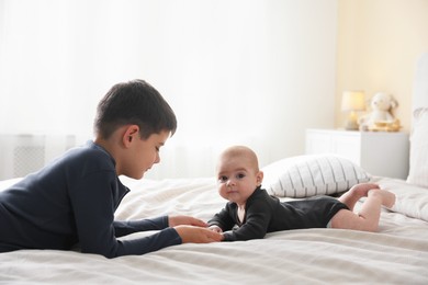 Photo of Cute little brothers holding hands on bed at home