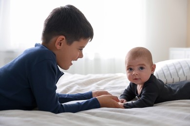 Photo of Cute little brothers holding hands on bed at home