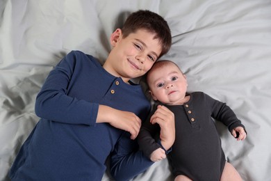 Photo of Cute little brothers on bed, top view