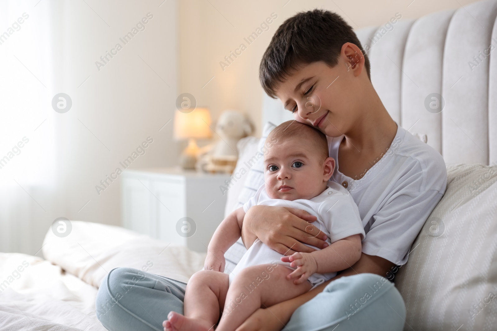 Cute little brothers sitting on bed at home Photo of Cute little brothers sitting on bed at home
