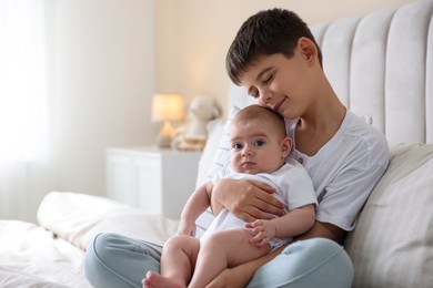 Photo of Cute little brothers sitting on bed at home