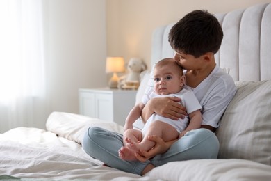 Photo of Cute little brothers sitting on bed at home