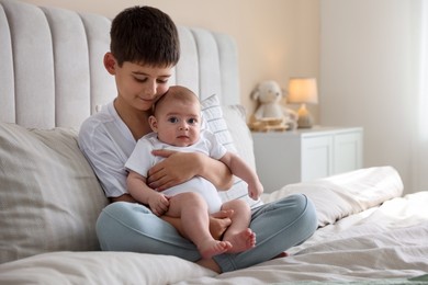Photo of Cute little brothers sitting on bed at home