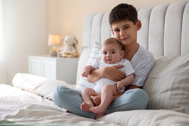 Photo of Cute little brothers sitting on bed at home