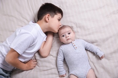 Photo of Cute little brothers on bed, top view