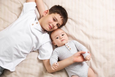 Photo of Cute little brothers on bed, top view