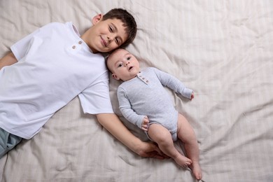 Photo of Cute little brothers on bed, top view