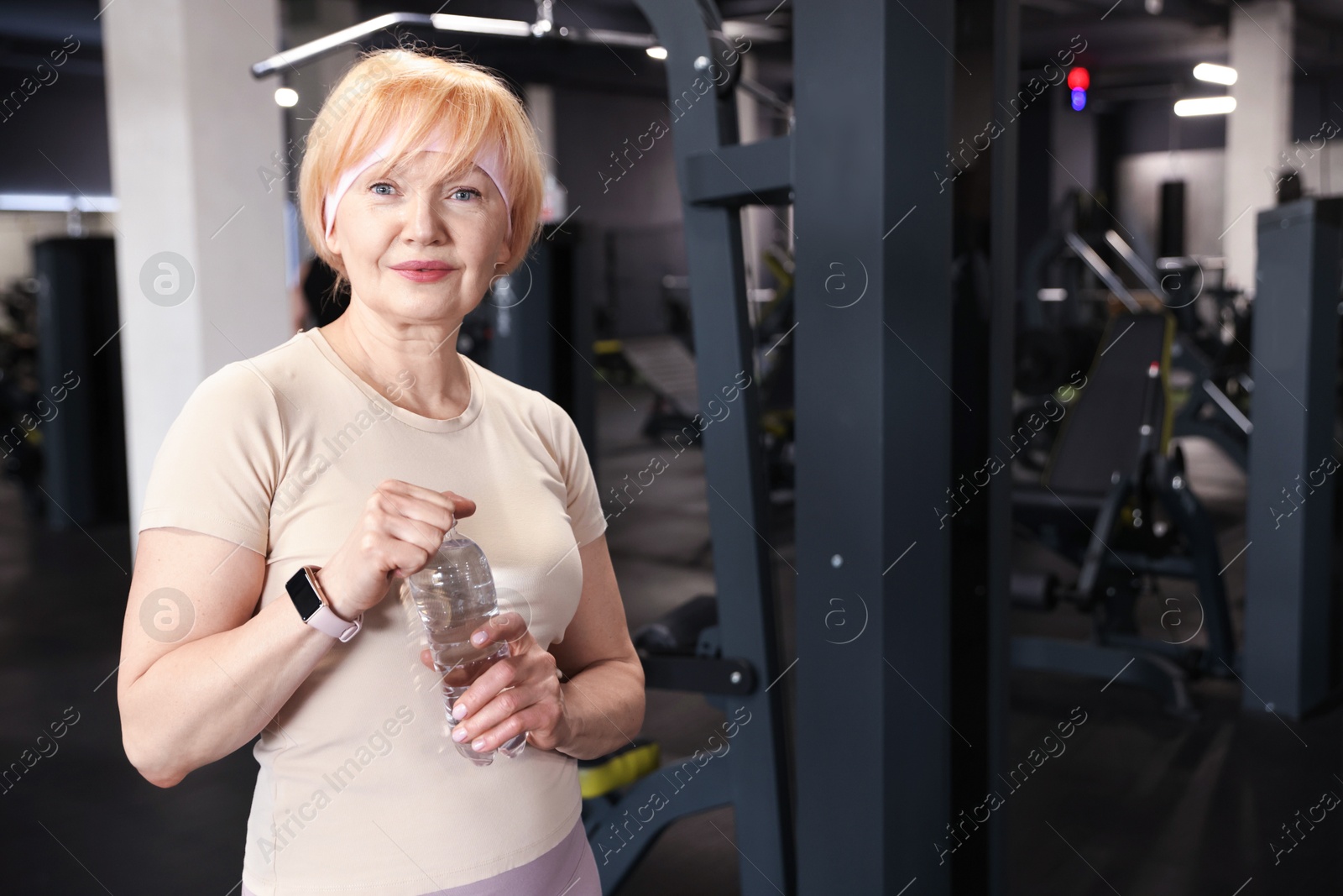 Senior woman with bottle of water in gym Photo of Senior woman with bottle of water in gym