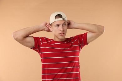 Photo of Young man in stylish baseball hat on beige background