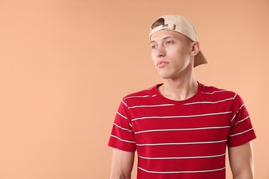 Photo of Young man in stylish baseball hat on beige background, space for text