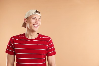 Photo of Young man in stylish baseball hat on beige background, space for text