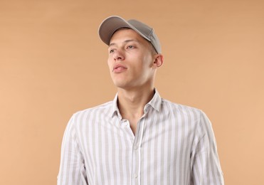 Photo of Young man in stylish baseball hat on beige background
