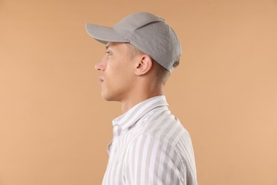 Photo of Young man in stylish baseball hat on beige background