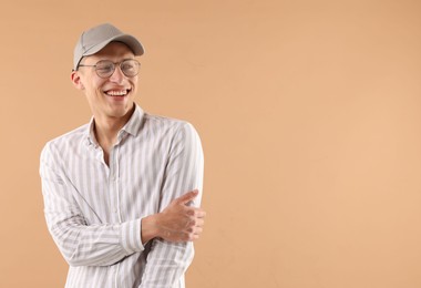Photo of Young man in stylish baseball hat on beige background, space for text